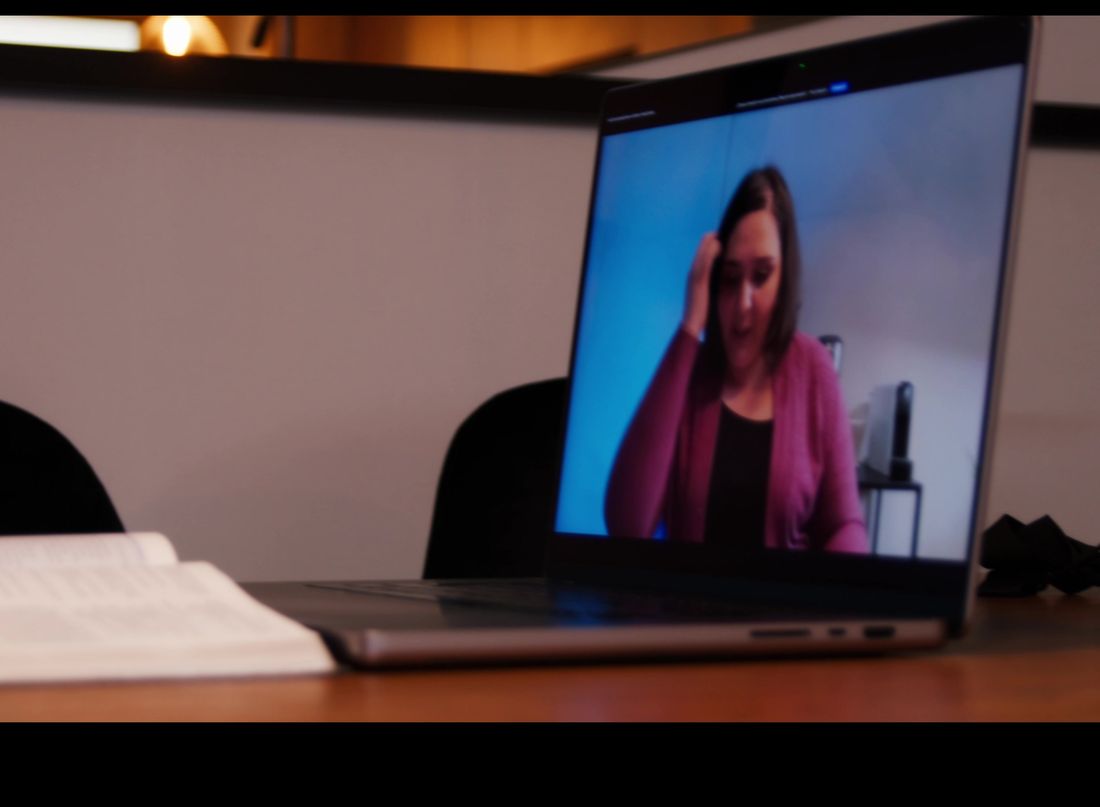 Una clase en vivo por Zoom en un notebook, junto a una Biblia abierta